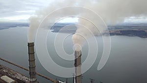 Aerial view of high chimney pipes with grey smoke from coal power plant. Production of electricity with fossil fuel.