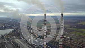 Aerial view of high chimney pipes with grey smoke from coal power plant. Production of electricity with fossil fuel.