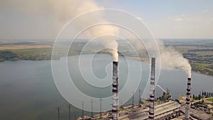 Aerial view of high chimney pipes with grey smoke from coal power plant. Production of electricity with fossil fuel.