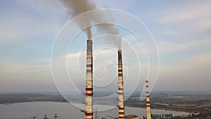 Aerial view of high chimney pipes with grey smoke from coal power plant. Production of electricity with fossil fuel