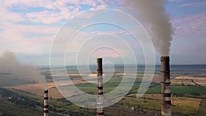 Aerial view of high chimney pipes with grey smoke from coal power plant. Production of electricity with fossil fuel