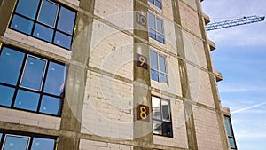 Aerial view of high residential apartment building with storey numbers on wall under construction. Real estate development.