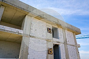 Aerial view of high residential apartment building with storey numbers on wall under construction. Real estate development