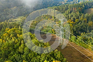 Aerial view of the high voltage power lines and high voltage electric transmission on the terrain surrounded by trees at