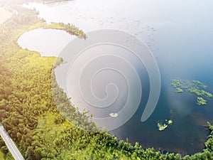 Aerial view of highway. Aerial view of a country road near the lake. Car passing by. Aerial road. Aerial view flying. Captured fro