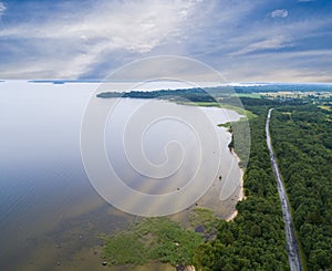 Aerial view of highway. Aerial view of a country road near the lake. Car passing by. Aerial road. Aerial view flying. Captured fro