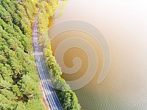 Aerial view of highway. Aerial view of a country road near the lake. Car passing by. Aerial road. Aerial view flying. Captured fro