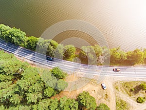 Aerial view of highway. Aerial view of a country road near the lake. Car passing by. Aerial road. Aerial view flying. Captured fro