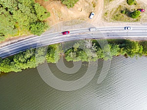 Aerial view of highway. Aerial view of a country road near the lake. Car passing by. Aerial road. Aerial view flying. Captured fro