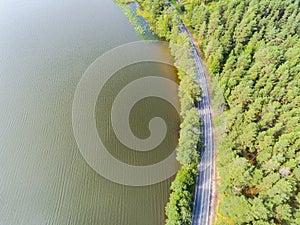 Aerial view of highway. Aerial view of a country road near the lake. Car passing by. Aerial road. Aerial view flying. Captured fro