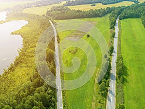 Aerial view of highway. Aerial view of a country road near the lake. Car passing by. Aerial road. Aerial view flying. Captured fro