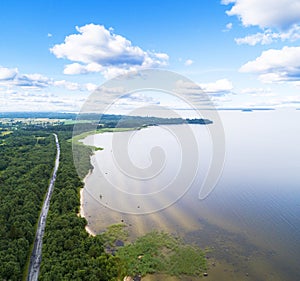 Aerial view of highway. Aerial view of a country road near the lake. Car passing by. Aerial road. Aerial view flying. Captured fro