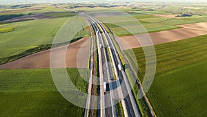 Aerial view of a highway with cars and trucks, in a beautiful countryside scenery.