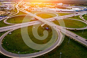 Aerial view at highway intersection or road junction with circle movement at sunset, cars and trucks traffic, drone shot