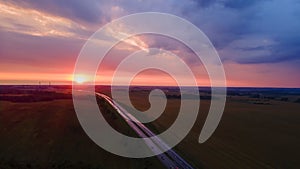 Aerial view of highway on red sunset. Landscape with road near countryside fields. Dramatic sky background