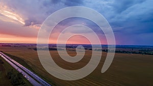 Aerial view of highway on red sunset. Landscape with road near countryside fields. Dramatic sky background