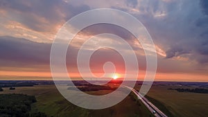 Aerial view of highway on red sunset. Landscape with road near countryside fields. Dramatic sky background