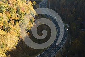 Aerial view of highway road in North Carolina through Appalachian mountains in golden fall season with fast moving