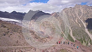 Aerial view of hiking team walking one by one, climbing up the mountain slope. Clip. Travel and sport lifestyle concept