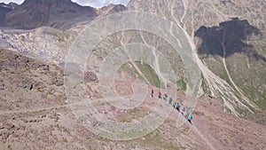 Aerial view of hiking team walking one by one, climbing up the mountain slope. Clip. Travel and sport lifestyle concept