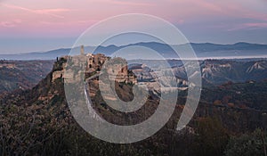 Aerial view of hilltop Civita di Bagnoregio village in Italy under pink sunset sky