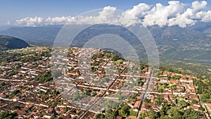 Aerial view of historic town Barichara, Colombia at a cliff edge with mountains and white clouds in background