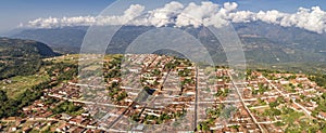 Aerial view of historic town Barichara, Colombia at a cliff edge with mountains and white clouds in background