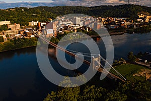 Aerial of Historic Wheeling Suspension Bridge + Downtown Buildings - Ohio River - Wheeling, West Virginia