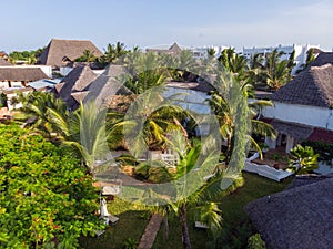 Aerial view on a Hotel near sandy beach behind green Palm trees. Coast of Indian ocean in Zanzibar, Africa