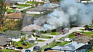 Aerial view of house on fire and firefighters extinguishing flames after short circuit caused spark to ignite wooden