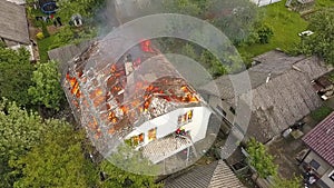 Aerial view of a house on fire with orange flames and smoke.