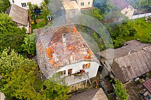 Aerial view of a house on fire with orange flames and white thick smoke