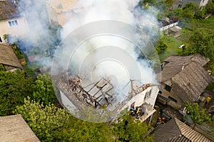Aerial view of a house on fire with orange flames and white thick smoke