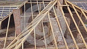 Aerial view of a house under construction works. Unfinished brick building with wooden frame for roof.