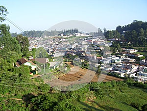Aerial view of houses, fields and Ooty town from the top of a hill