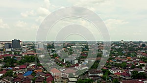 Aerial view of houses surrounded by trees captured on a bright cloudy day