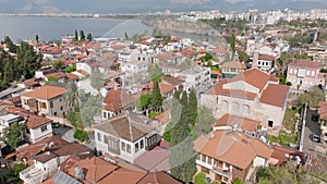 Aerial view of houses with tiled roofs. Sehzade Korkut Mosque with minaret. housing estate at sea coast in background