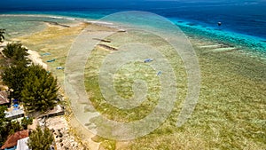 Aerial view of a huge coral reef table forming a fringing reef around a tropical island