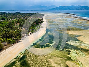 Aerial view of a huge coral reef table forming a fringing reef around a tropical island