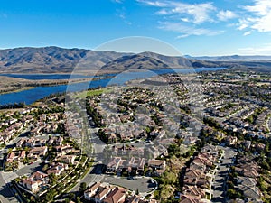 Aerial view of identical residential subdivision house with big lake and mountain on the background during sunny day
