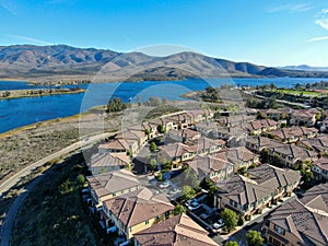 Aerial view of identical residential subdivision house with big lake and mountain on the background during sunny day