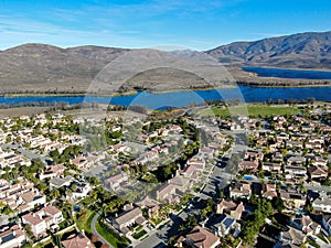 Aerial view of identical residential subdivision house with big lake and mountain on the background during sunny day