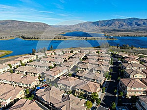 Aerial view of identical residential subdivision house with big lake and mountain on the background during sunny day