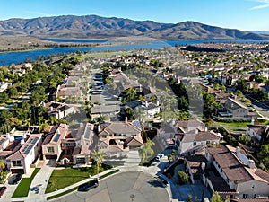 Aerial view of identical residential subdivision house with big lake and mountain on the background during sunny day