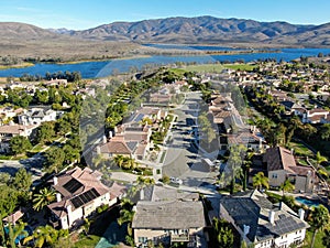 Aerial view of identical residential subdivision house with big lake and mountain on the background during sunny day