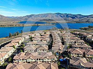 Aerial view of identical residential subdivision house with big lake and mountain on the background during sunny day