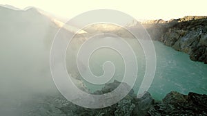 Aerial view of Ijen volcano at sunrise, acid lake with turquoise water in crater