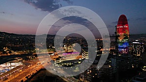 Aerial view of illuminated multicolored Torre Agbar with night cityscape on background