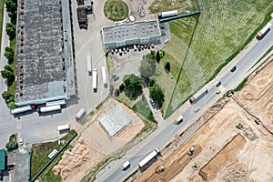 Aerial view of industrial buildings and trucks with cargo trailers