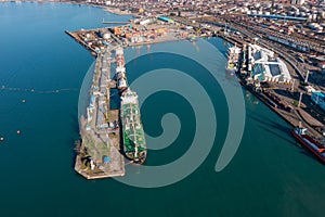 Aerial view industrial cargo and fuel port with ship tanker vessel loading in gas and oil terminal station refinery